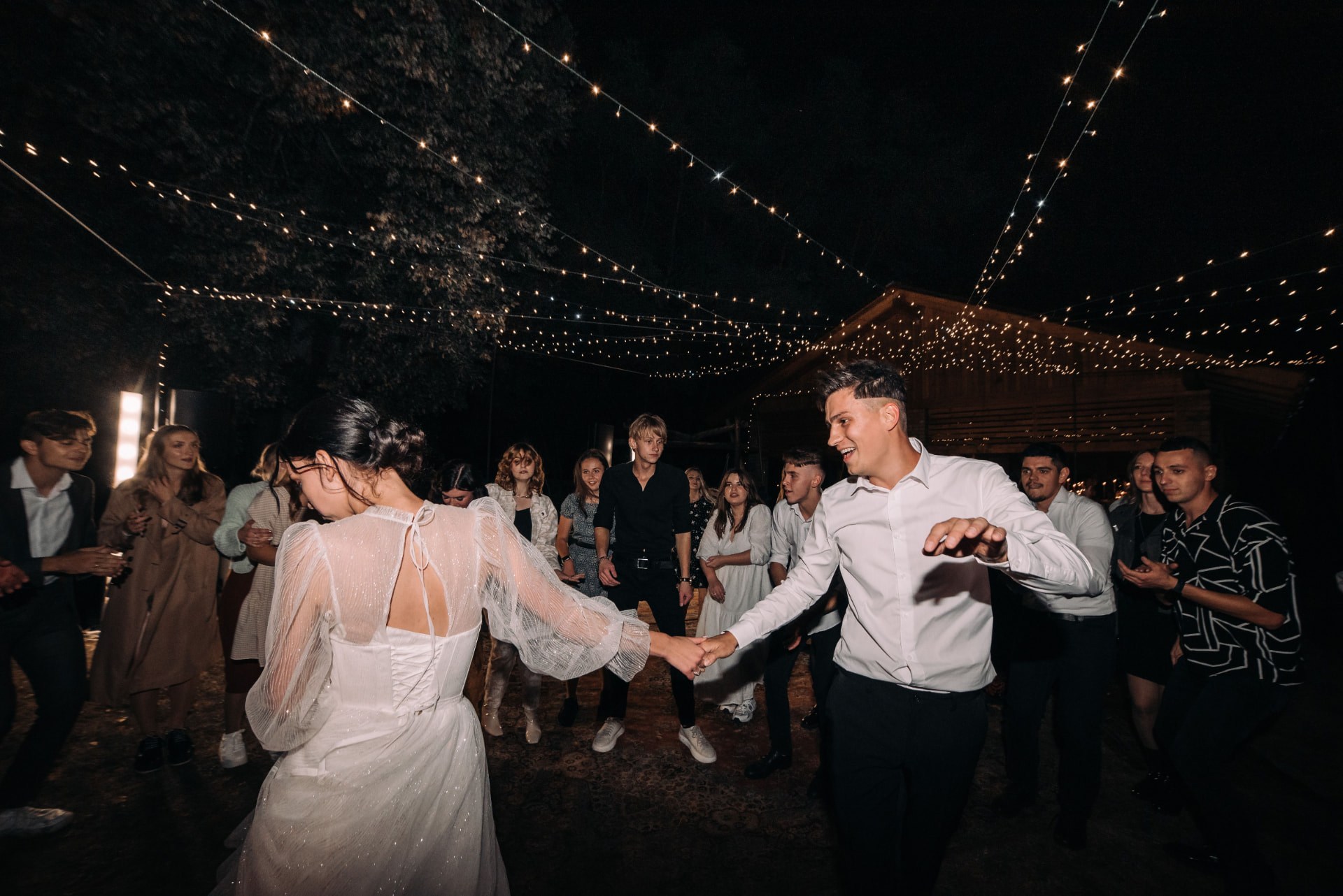 Bride and groom sharing their first dance under string lights